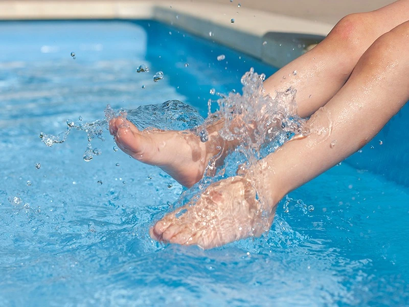 photo de pieds jouant avec l'eau dans une piscine