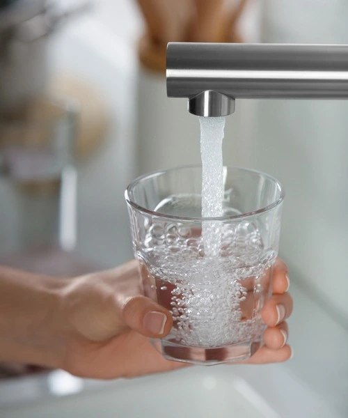 Person who fills a glass of water from a tap